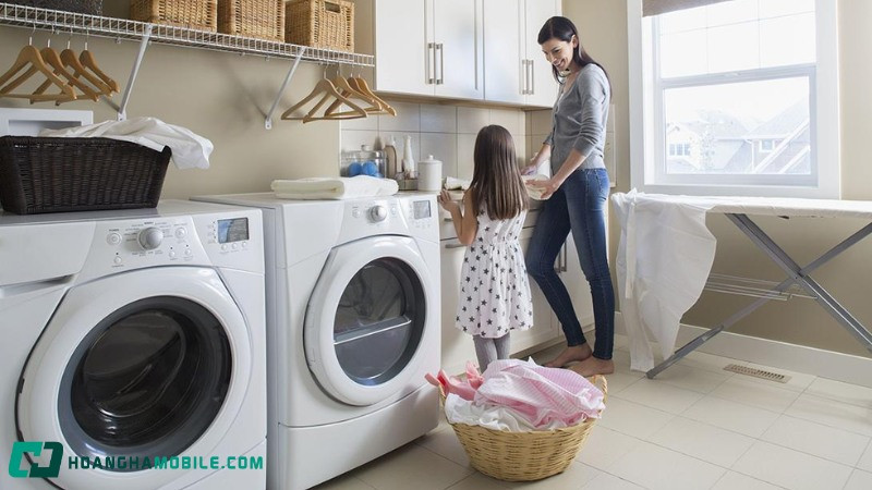 Một người đứng cạnh chiếc máy giặt cửa trước hiện đại, biểu thị sự đầu tư xứng đáng cho thiết bị gia đình chất lượng cao