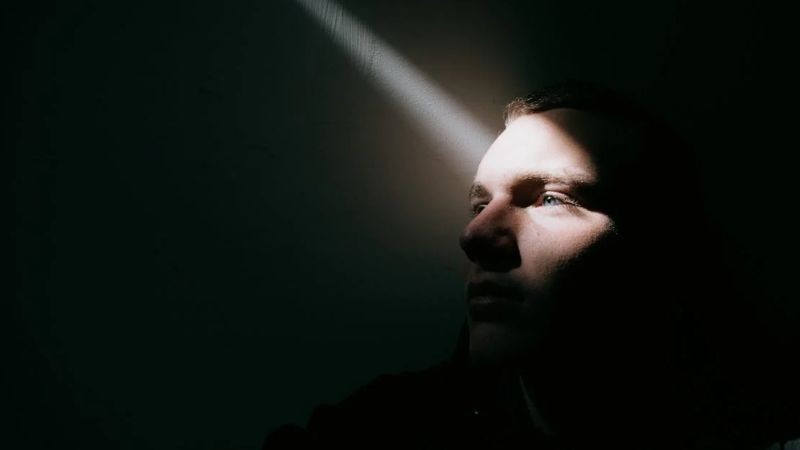 Một người ngồi trong góc tối, thể hiện sự cô đơn và buồn bã