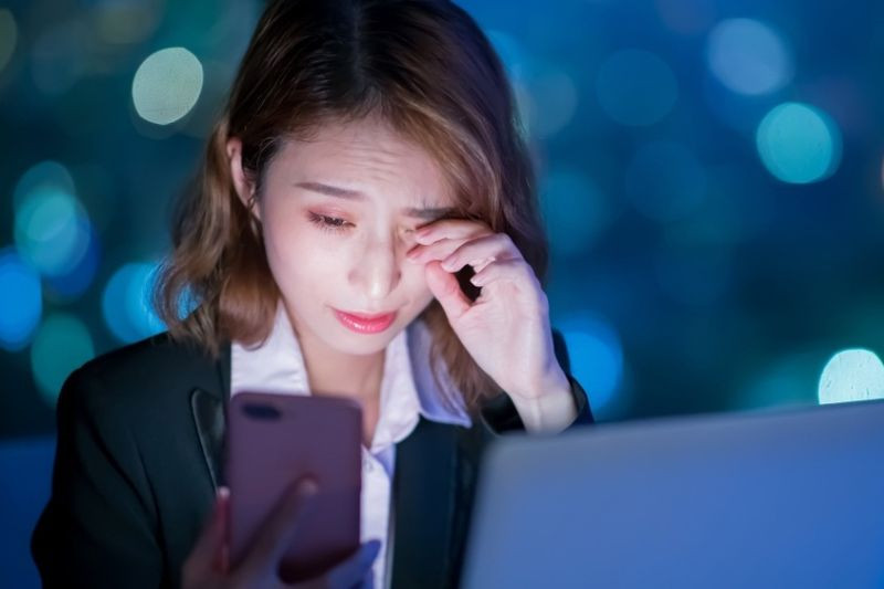 Người phụ nữ dụi mắt khi sử dụng laptop vào buổi tối, minh họa sự mệt mỏi do ánh sáng xanh màn hình