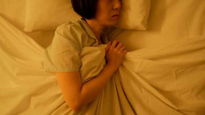 Người phụ nữ nằm một mình trên giường, thể hiện sự cô đơn và mệt mỏi