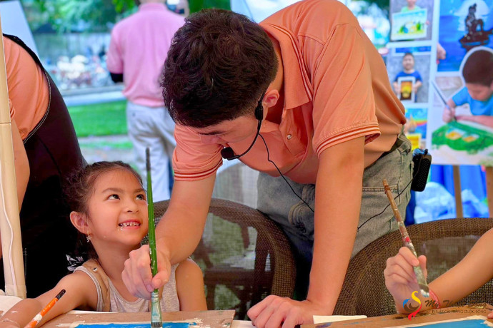 Nhóm các bé thiếu nhi ngồi vẽ tranh cùng nhau trên bãi cỏ