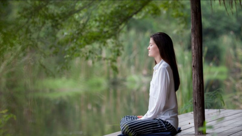 Tay người đang thực hành thiền với ánh sáng, tượng trưng cho sự kết nối tâm linh và chữa lành tâm hồn.