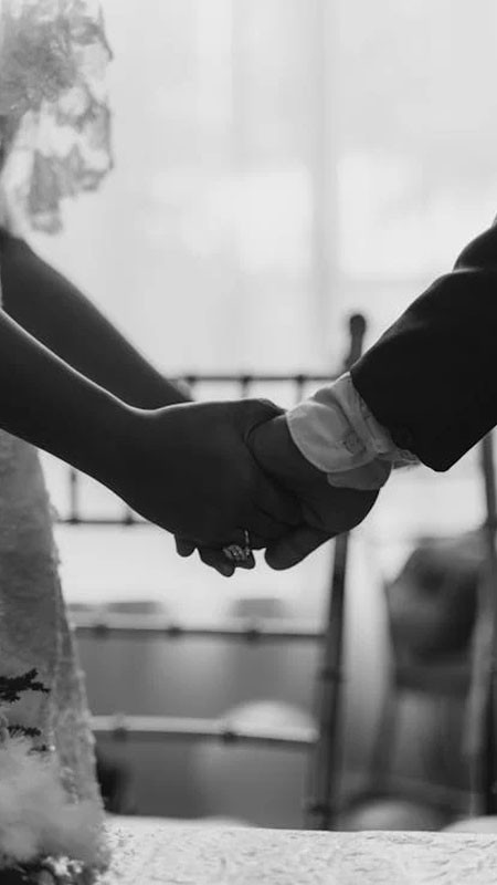 Tay người nữ nhẹ nhàng đặt lên tay người nam, cả hai đều đeo nhẫn