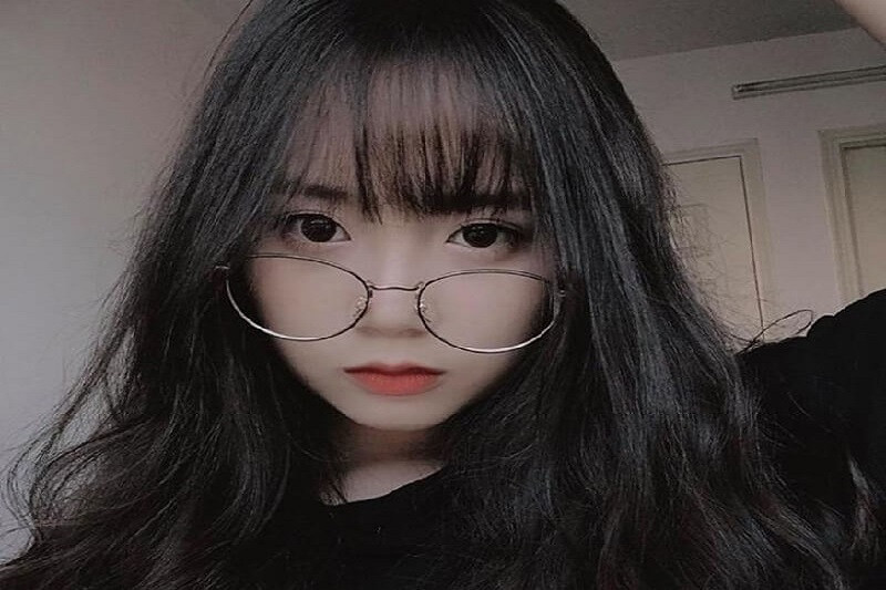 Thiếu nữ đeo kính gọng tròn nhìn về phía xa