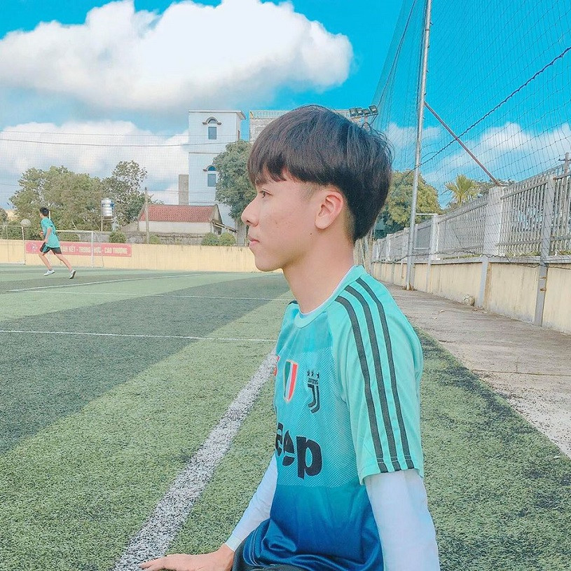 Trai đá bóng mặc áo đấu màu xanh trên sân cỏ