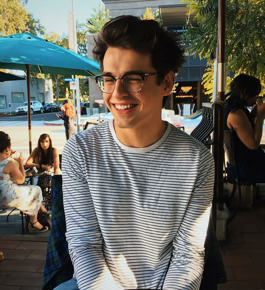 Trai đẹp đeo kính tròn cười tươi, thể hiện sự đáng yêu