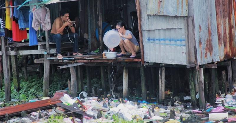 Bức tranh vẽ dòng sông ô nhiễm nặng nề với rác thải nổi lềnh bềnh và nước đen kịt