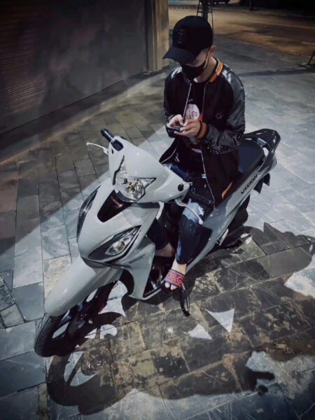 Chàng trai ngồi trên chiếc xe Wave trắng trong con hẻm thành phố