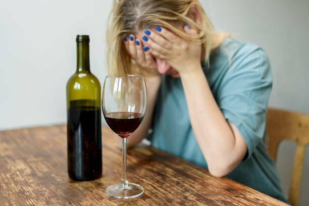 Cô gái ngồi uống bia, dáng vẻ mệt mỏi và buồn bã