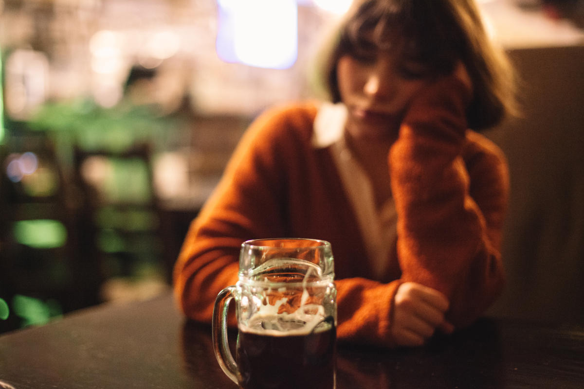 Cô gái ngồi uống bia trong quán, ánh mắt nhìn xa xăm đầy tâm trạng