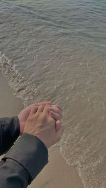 Hai bàn tay nắm chặt trên bờ cát trắng dưới ánh nắng