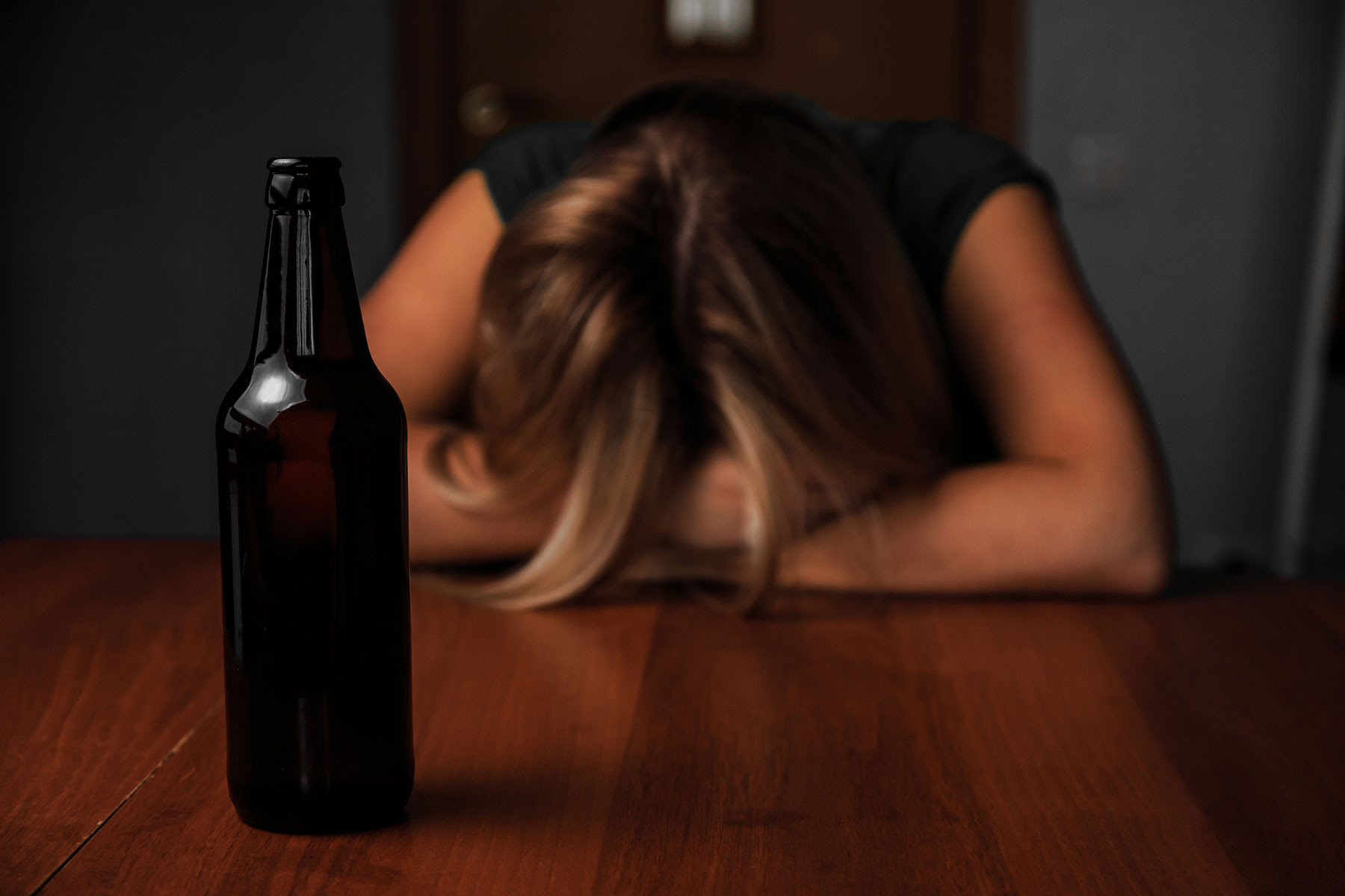 Hình ảnh cô gái gục đầu xuống bàn với chai bia, thể hiện sự mệt mỏi và buồn bã