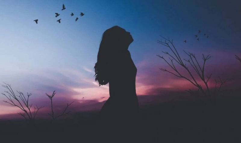 Hình ảnh một người ngồi cô đơn nhìn xa xăm, thể hiện tâm trạng buồn bã và suy tư