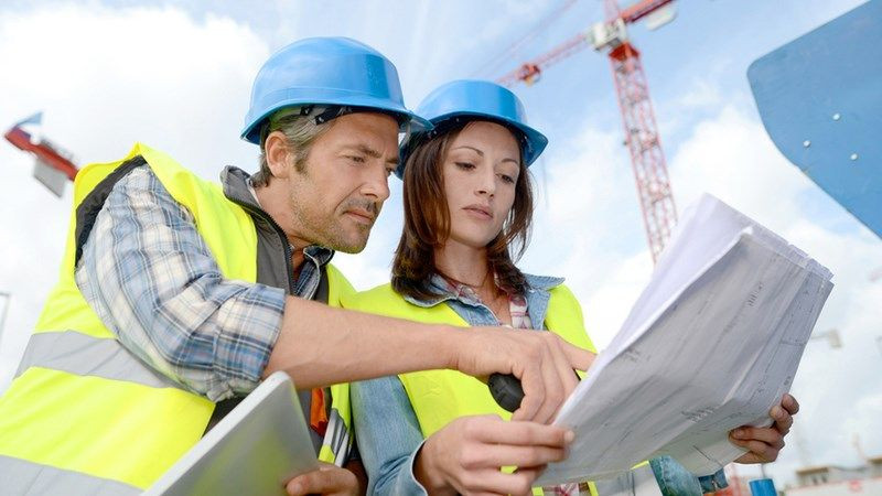 Kỹ sư dự toán QS đang làm việc với bản vẽ và tài liệu liên quan đến quản lý chi phí xây dựng