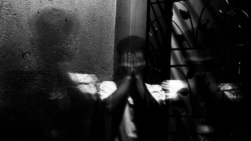 Một người ngồi một mình trong bóng tối, thể hiện cảm giác cô đơn và tâm trạng buồn bã